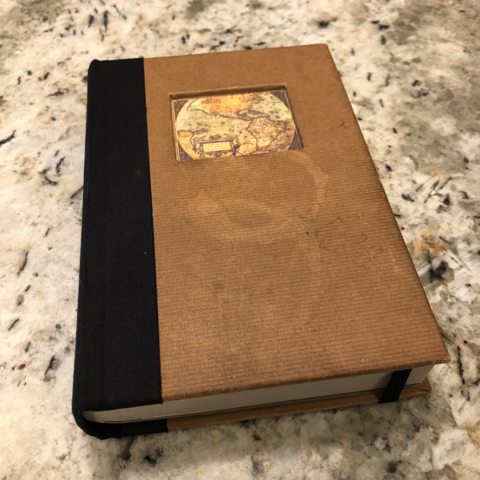 A small brown journal, with many pages and an old map of the world on the cover