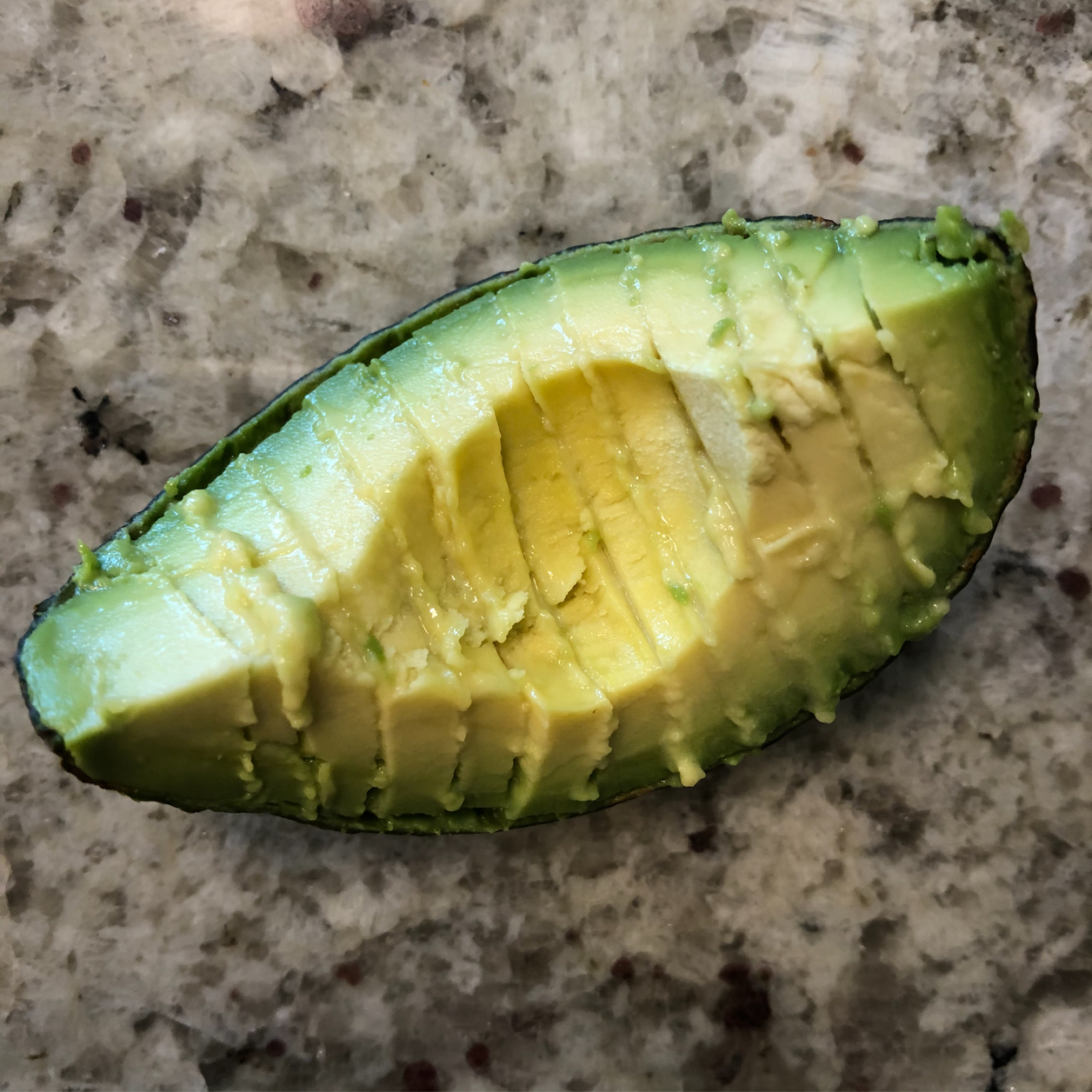 Closeup of a quarter section of avocado, pitted and sliced