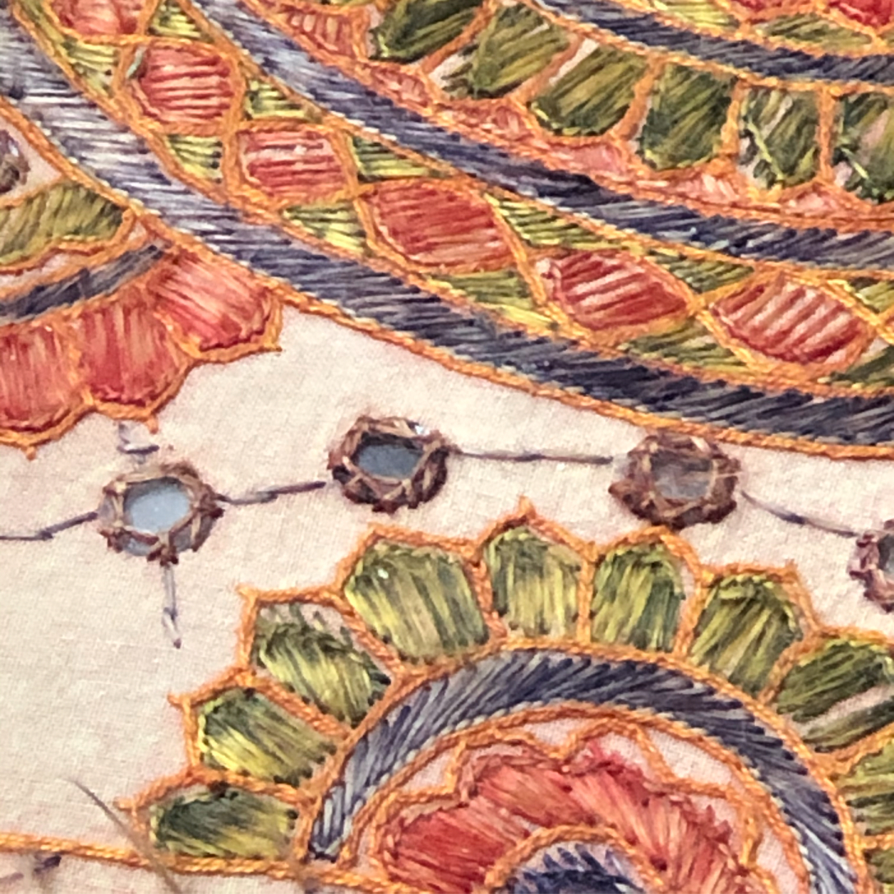 Close up of colorful embroidery shaped like wheels on a linen background