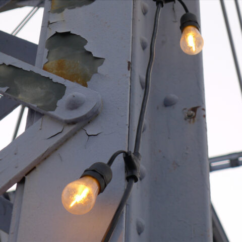 two yellow lightbulbs on a rusted steel bridge