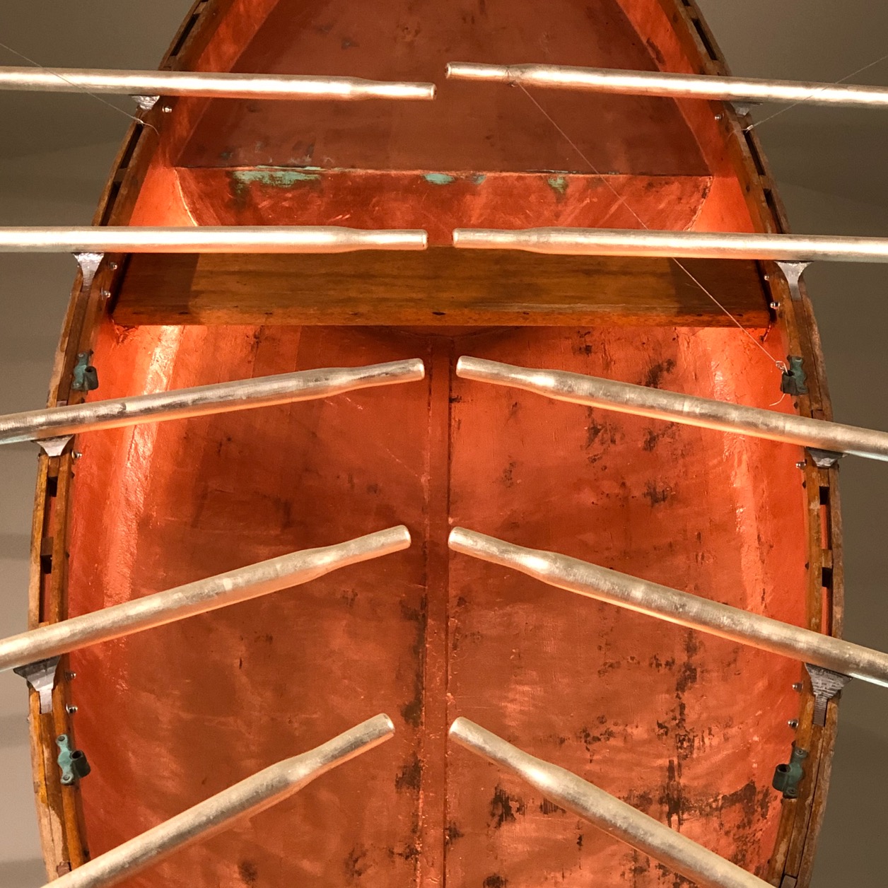 A canoe with and orange interior and golden oars, from the Bill Reid art museum