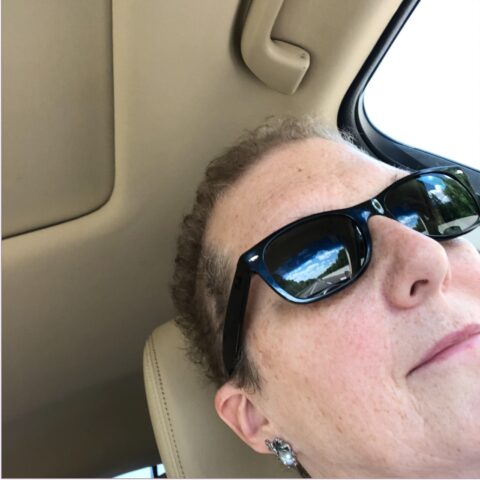 Jule, in sunglasses, in her car