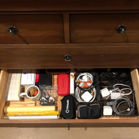 A dresser drawer with cables and other items organized into specific compartments