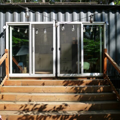 exterior of cabin showing two sliding glass doors with wooden steps down to a deck