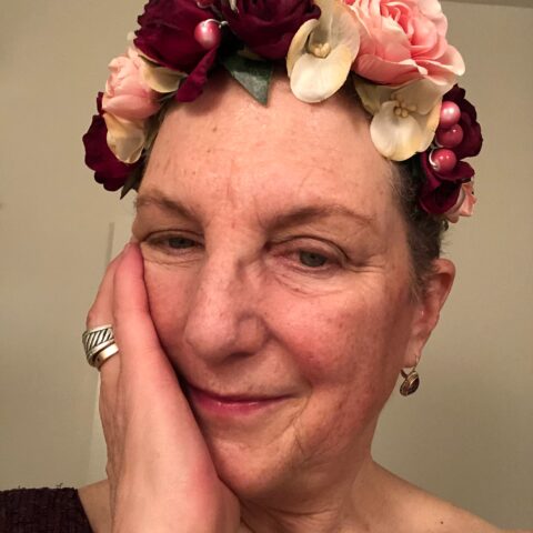 Jule Kucera, headshot, wearing a crown of fabric flowers