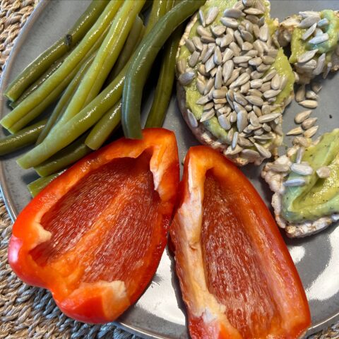 green beans, red pepper and avocado toast with sunflower seeds on a plate
