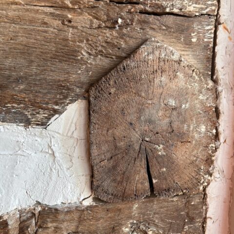 Close up of wide hand-hewn log wall with white filler